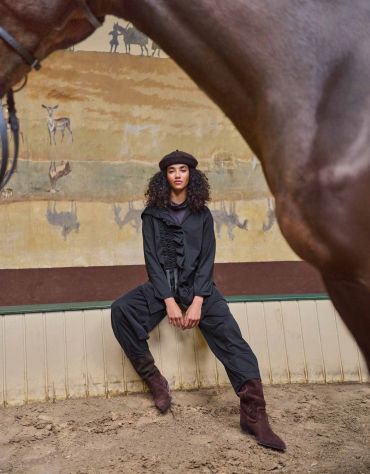 Woman sitting with horse framing the image.