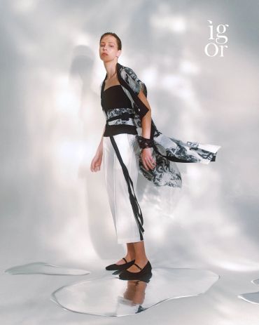 Model wearing a stylish black and white outfit with flowing fabric.