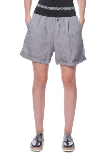 Woman wearing pinstriped shorts and shiny shoes.