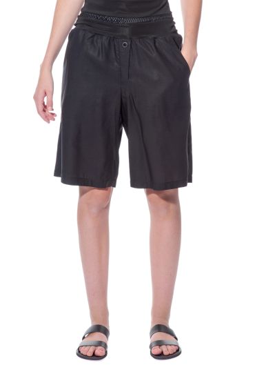 Woman wearing black knee-length shorts and black sandals.