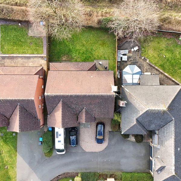 Aerial view of suburban houses with gardens and parked cars.