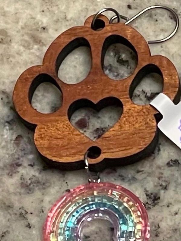 Wooden paw print keychain with a heart cutout and attached rainbow charm.