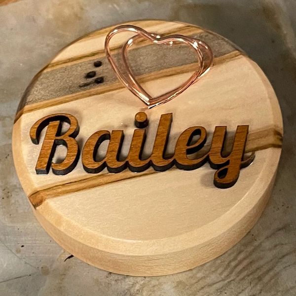 Round wooden plaque with the name Bailey and a metal heart on top.