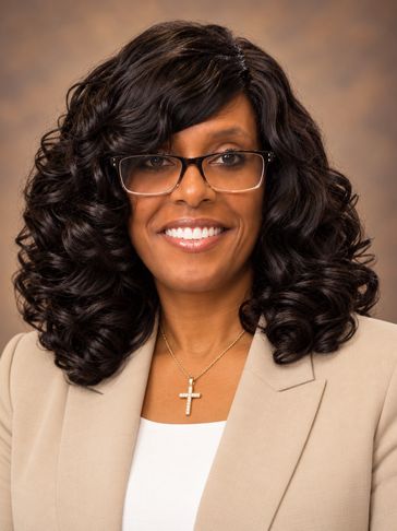 Professional woman with glasses and curly hair.