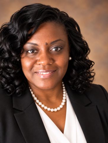 Professional portrait of a smiling woman with pearl necklace.