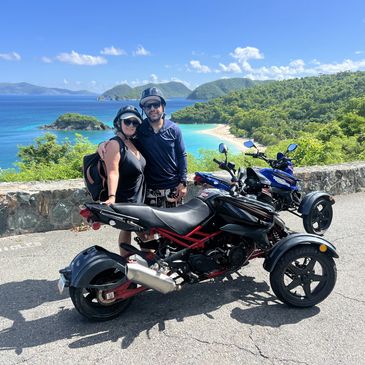 Couple posing with three-wheeled motorcycles by a scenic tropical coastline.