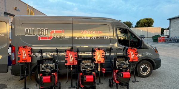 Work vans and equipment for All Pro Systems Ltd parked outdoors at sunset.