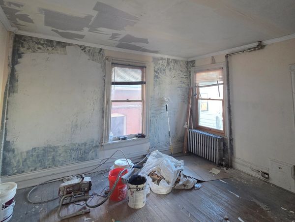Room under renovation with painting supplies and partially painted walls.