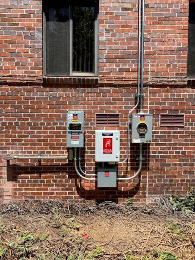 Electrical meters and panels mounted on a brick wall.