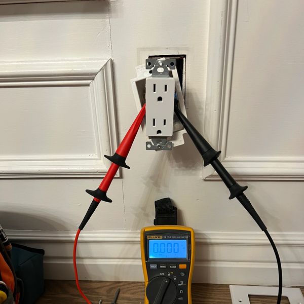 Multimeter measuring voltage on an exposed outlet.