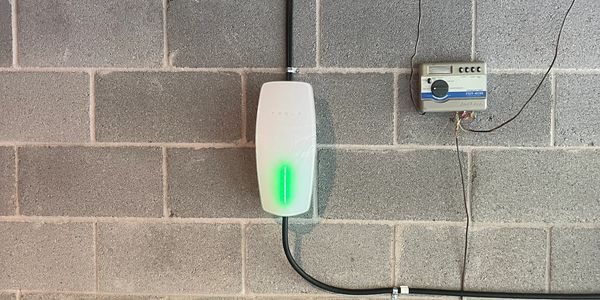 White device with green light on a concrete wall.