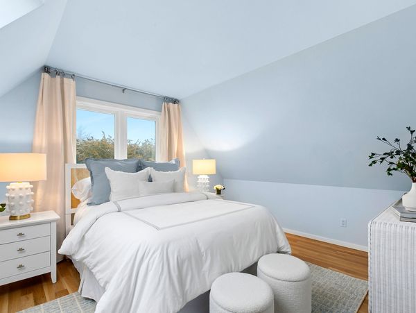 "After" image of Hamptons bedroom after home staging, with sky blue walls and elegant white and blue