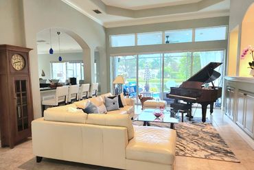 Photo of luxury living room with large sectional, baby grand piano and blue and white accents. 