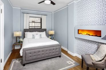 Home staging image of luxurious blue bedroom with wallpaper accent wall and fireplace