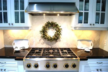 Home staging image of classic white kitchen with marble backsplash and black counters.