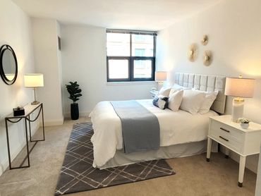Home staging image of a luxurious NYC bedroom with white bedding, blue details and gold accents