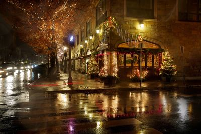 Festive street corner decorated with Christmas lights on a rainy night.