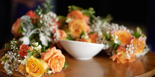 Bouquets of orange and yellow roses with white baby's breath on a wooden table.