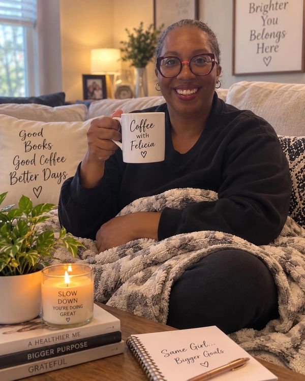 Felicia sitting on a couch holding a "Coffee with Felicia" mug.