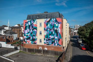 Colorful abstract mural painted on the side of a residential building.