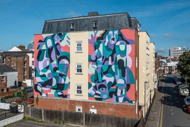 Colorful abstract mural painted on the side of a residential building.