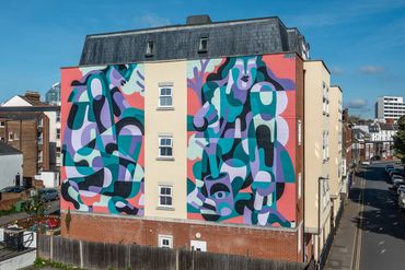 Colorful abstract mural painted on the side of a residential building.