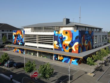 Modern building with colorful abstract murals on its walls under clear blue sky.