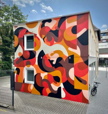 Colorful abstract mural covers the side of a building.