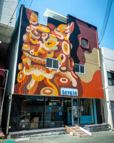 Colorful mural of a traditional lion mask on a building facade.