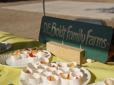 D.E. Boldt Family Farms' table with fresh stone fruit samples.