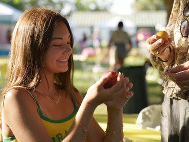 A girl enjoying a ripe plum.