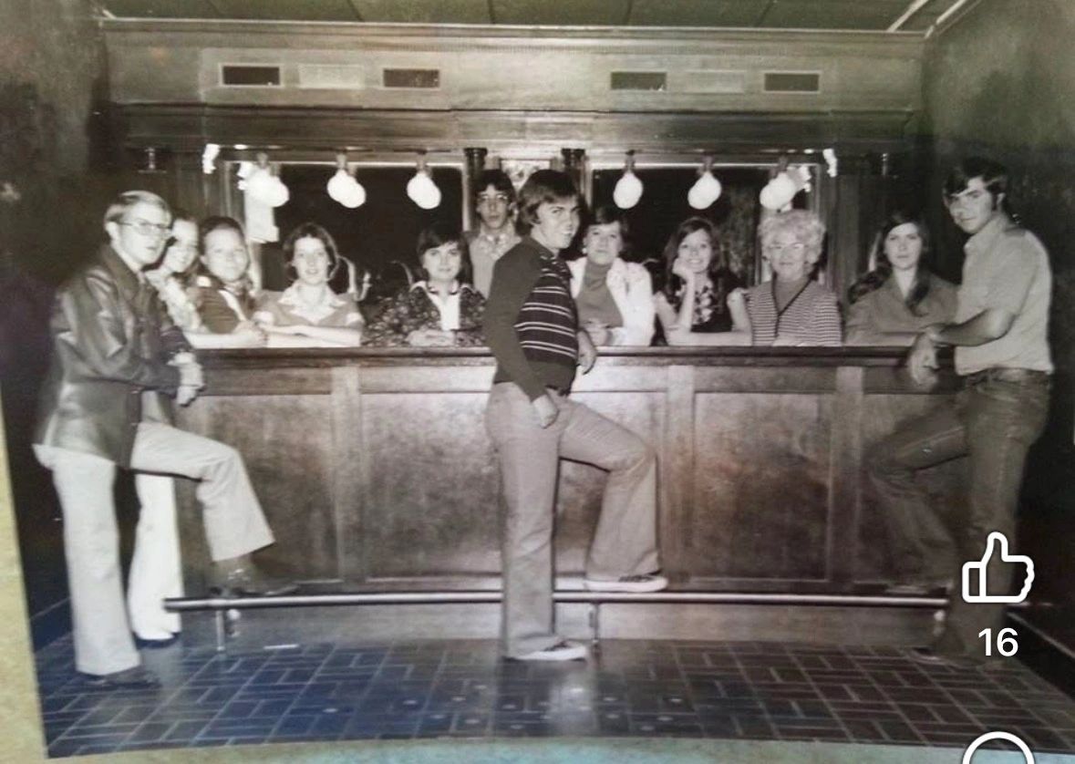 A vintage black and white photo of people posing at a bar.