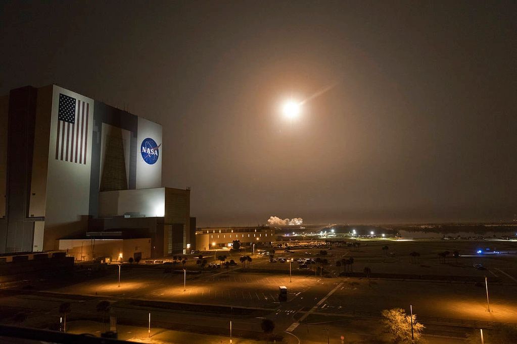 Nighttime rocket launch near NASA building.