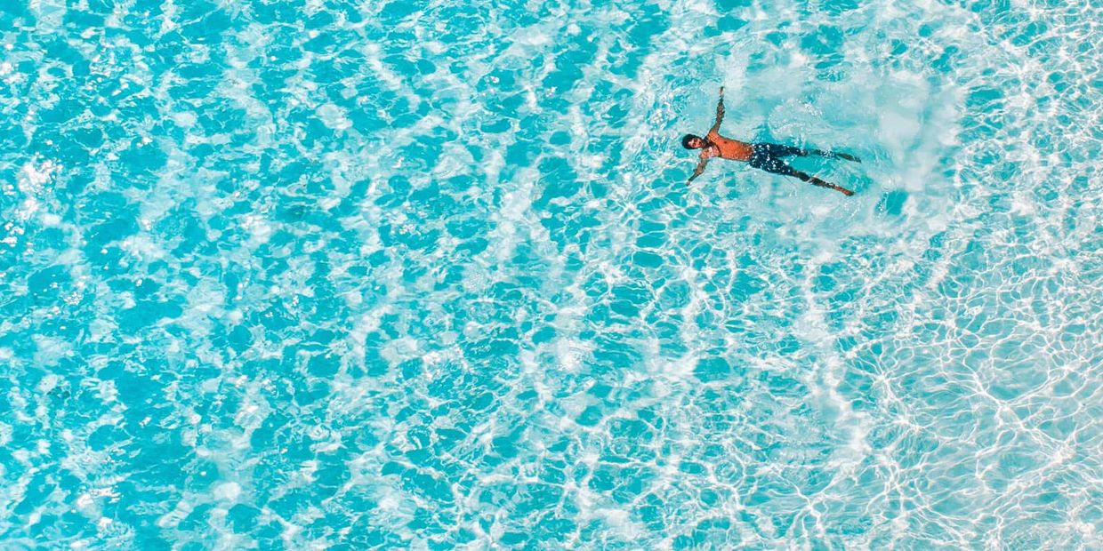 Person floating in the ocean, evocative of fluid movement and connection to nature.