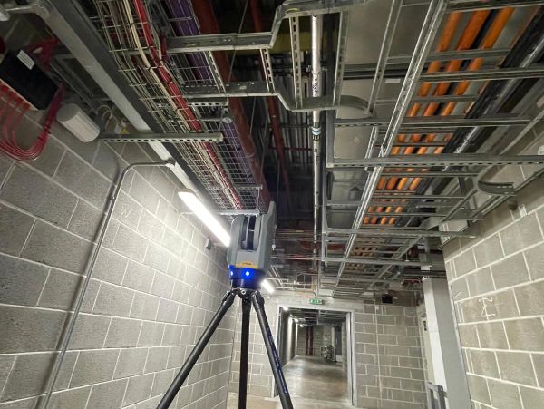 Laser scanner tripod in industrial hallway.