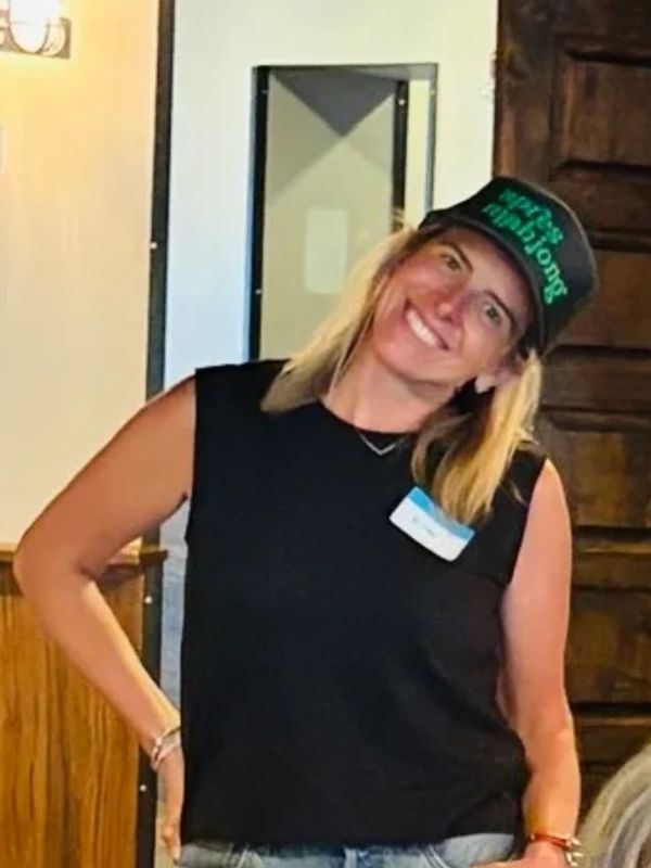 Smiling woman in a black sleeveless top and cap posing indoors.