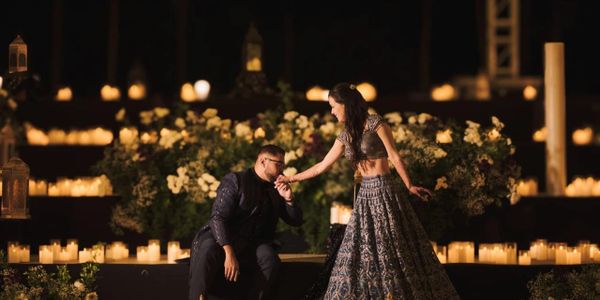 A romantic moment with a man kissing a woman's hand surrounded by candles.