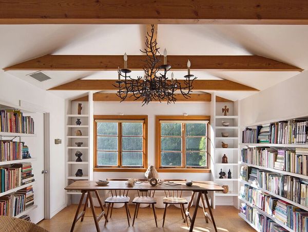 Cozy wooden-beam study room with central table and bookshelves.