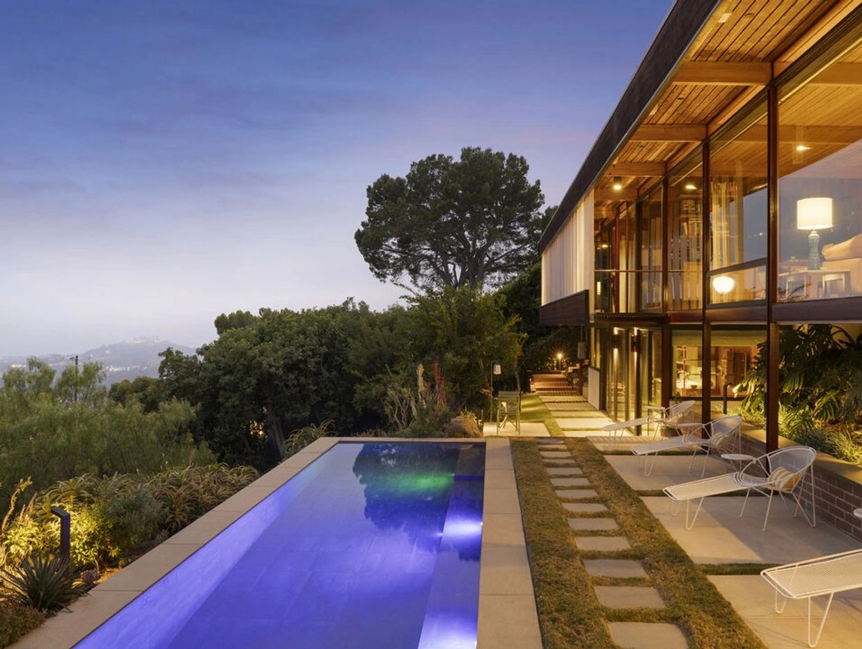 Modern house with infinity pool at sunset.
