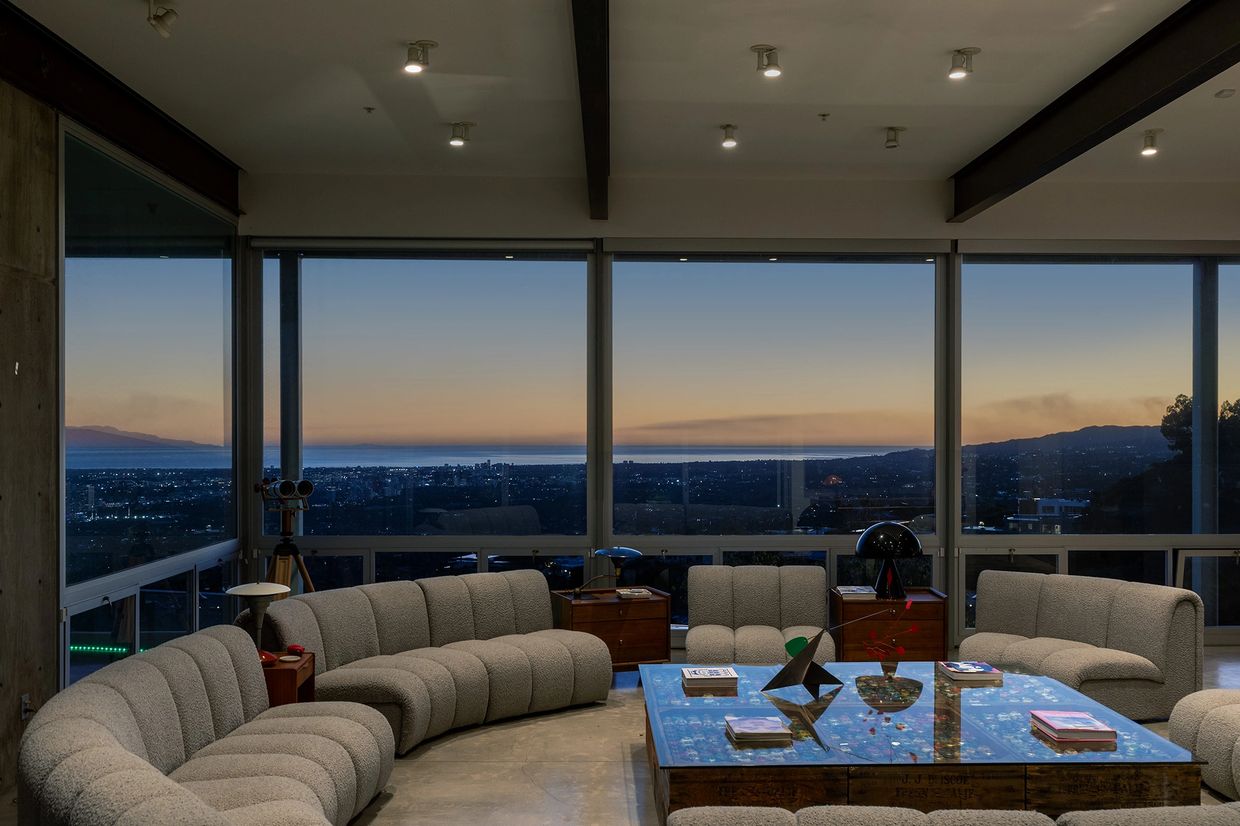 Modern living room with panoramic city view at dusk.