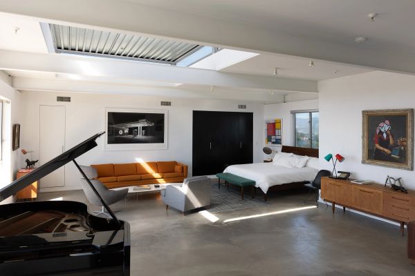 Modern open-concept living space with piano and bed.
