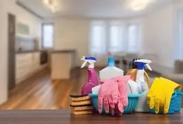 Cleaning supplies and gloves on a table in a bright kitchen.