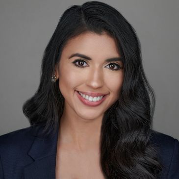 Professional headshot of a smiling woman with long black hair.