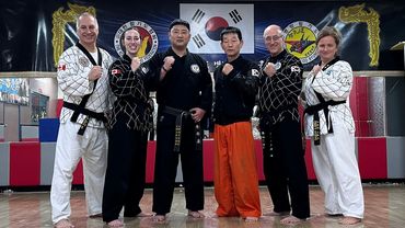 A group of martial artists posing in a dojo with fists raised.