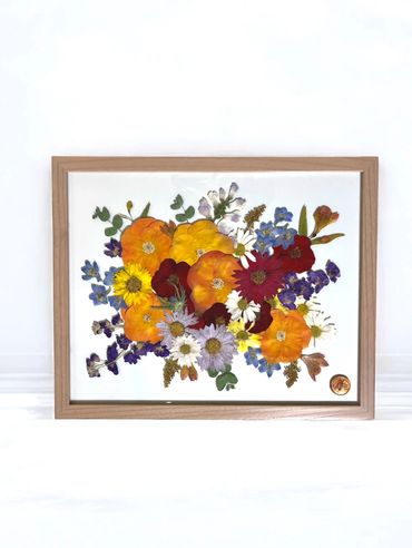 Framed artwork of vibrant, pressed flowers in various colors.