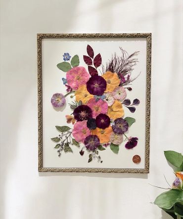 Framed artwork of vibrant pressed flowers in various colors and shapes.