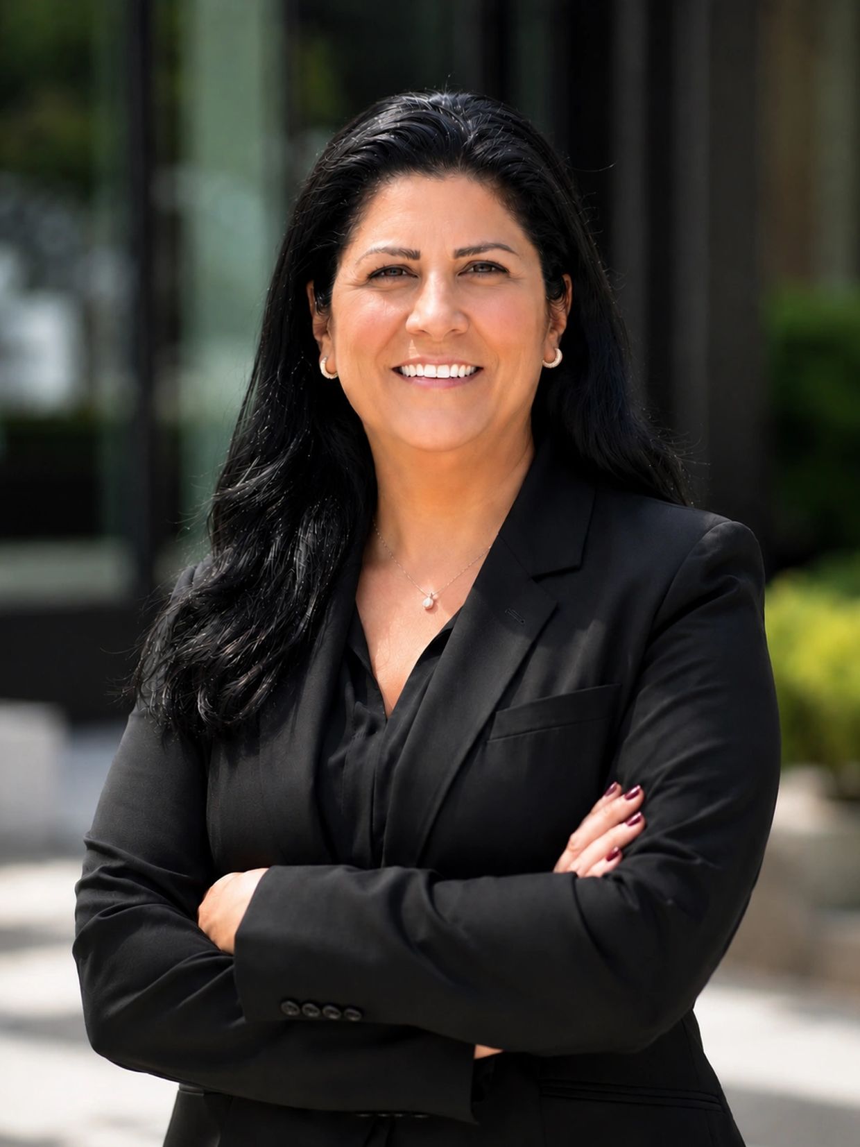 Smiling woman in black blazer with crossed arms.