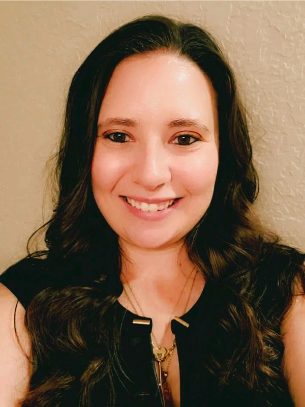 Smiling woman with long brown hair and black top.