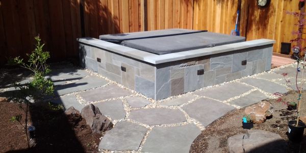 Stone hot tub with wooden fence background.