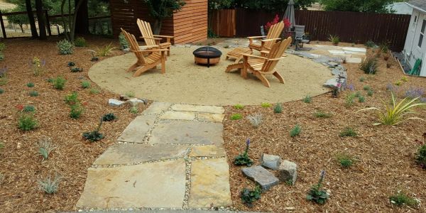 Backyard seating area with wooden chairs and fire pit.